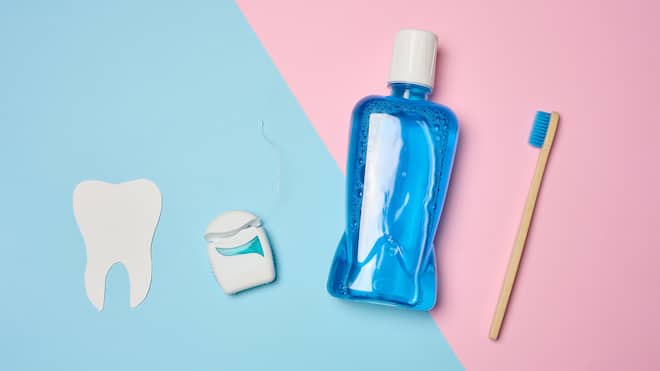 Was uns die Zahnfee verschwieg Auf einer Oberfläche liegt ein Zahn, eine Packung Zahnseide, eine Flasche Mundspülung und eine Zahnbürste. Ist Zahnseide gut oder schlecht für die Zahnpflege? Was wirklich stimmt und was in den Bereich Mythos gehört