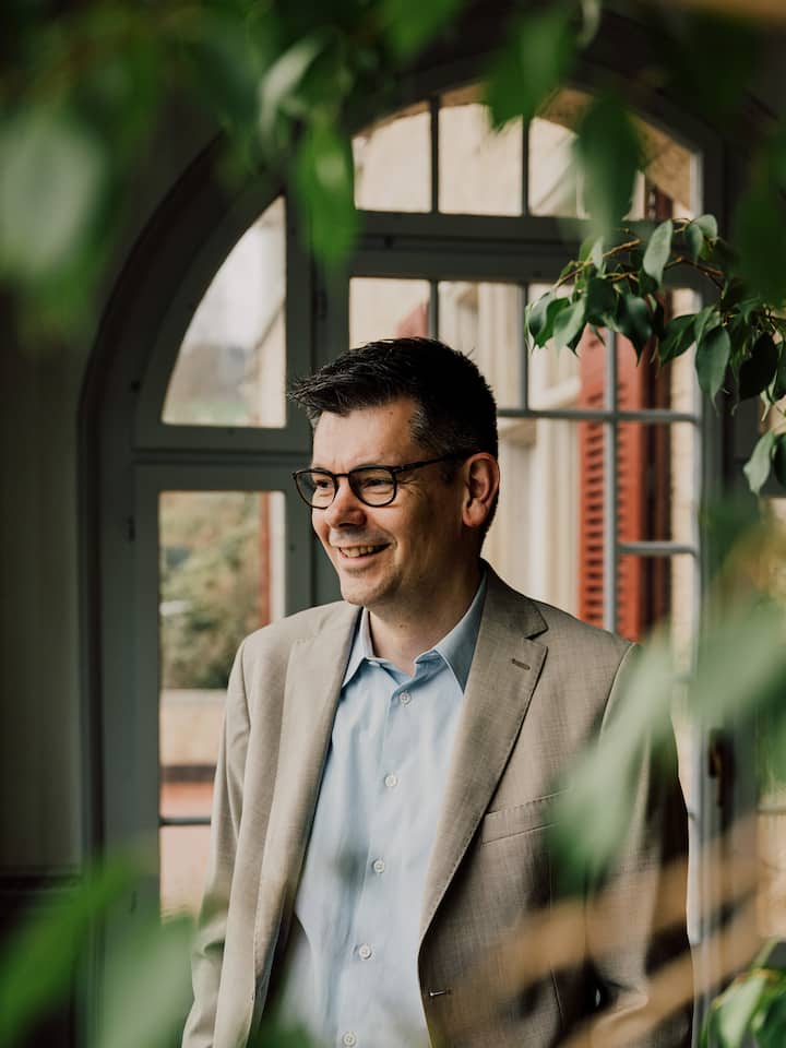 Der reformierte Pfarrer Christian Scharpf posiert vor einem Fenster. Christian Scharpf verlor als Kind seinen Vater. Er hat seinen Frieden damit gemacht – auch dank Kampfkunst. Und einem Armeeseelsorger.