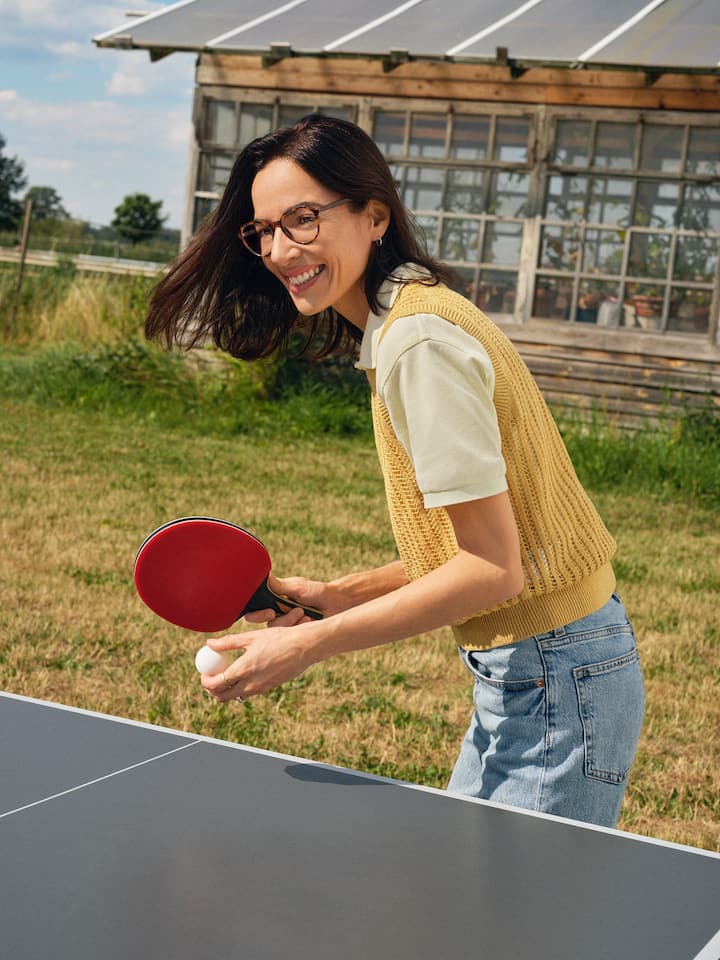 Frau mit Brille beim Ping-Pong spielen