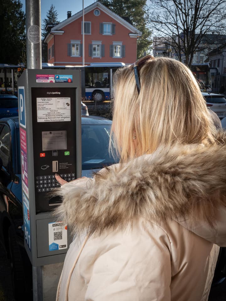 Die Denner-Kundin von hinten bei der Parksäule - Eine Denner-Kundin parkiert auf dem Denner-Parkplatz. Trotzdem verlangt eine Sicherheitsfirma 50 Franken Umtriebsentschädigung. So nicht, sagt der Beobachter