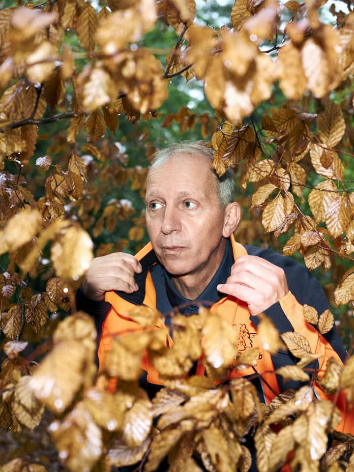 Portät von Förster Urs Steck, fotografiert durch Äste mit trockenem Laub.