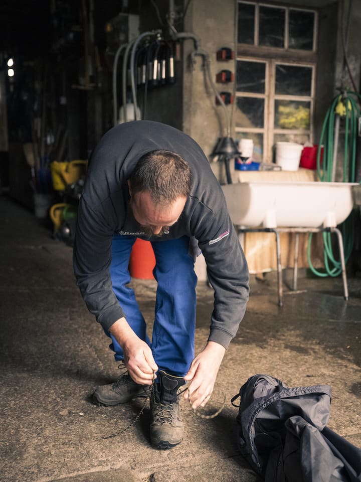 Reto Brunner bindet sich die Schuhe - Reto Brunner leidet an einer bipolaren Störung. Statt in der Klinik lebt er nun bei einer Gastfamilie im Berner Oberland. Die Arbeit im Stall gibt ihm Halt. Ein Besuch zeigt, wie Care Farming funktioniert