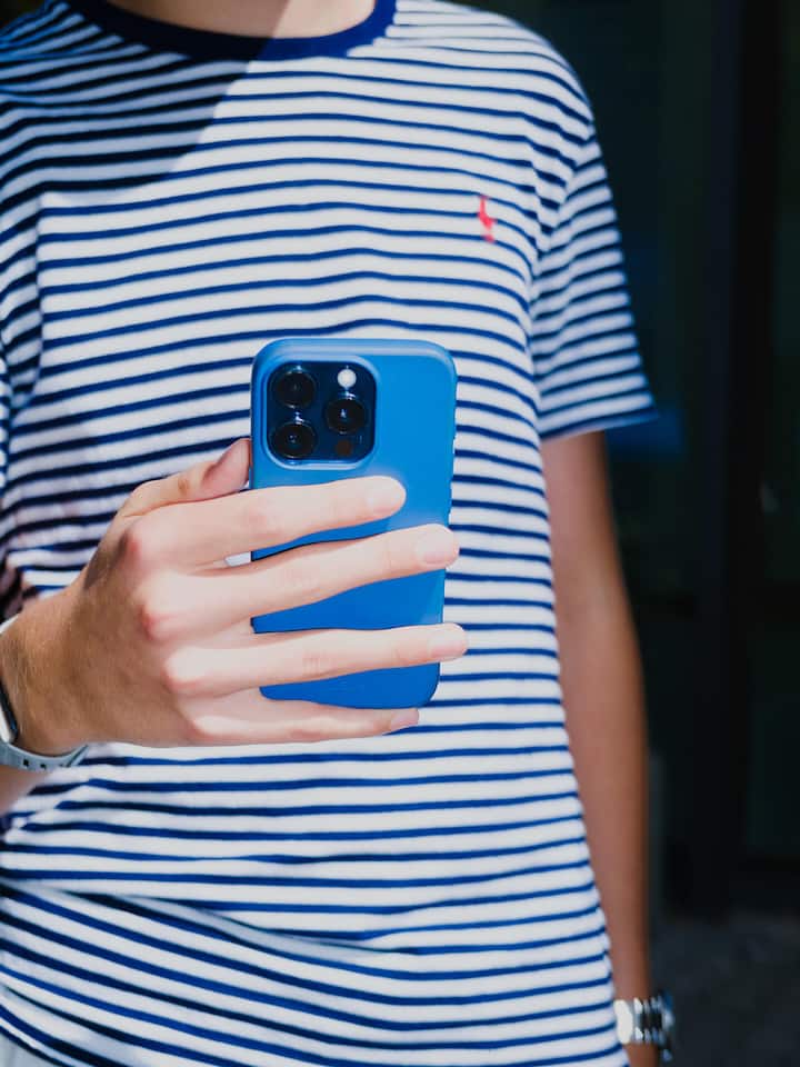 Ein Jugendlicher hält ein Smartphone vor seiner Brust.