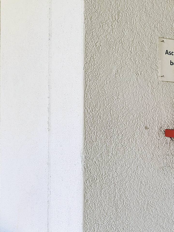 Ein Aschenbecher an einer Wand mit der Beschriftung "Aschenbecher benutzen!"