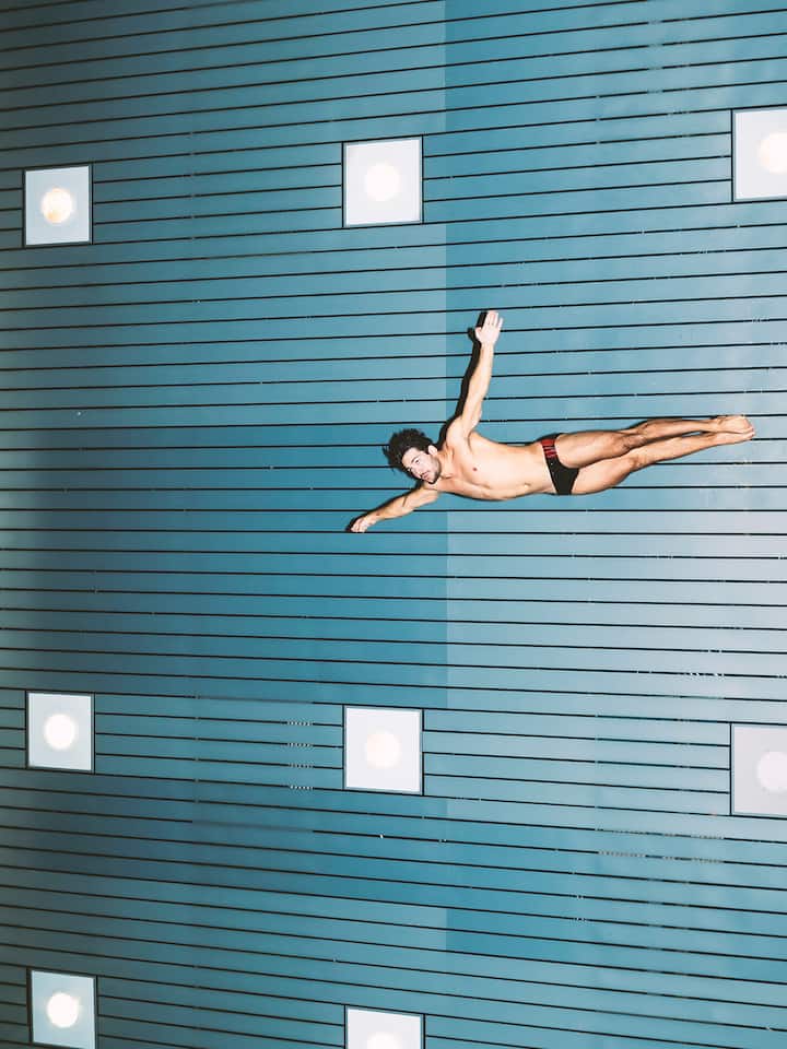 Ein Mann in Badehose springt kopfvoran nach unten.