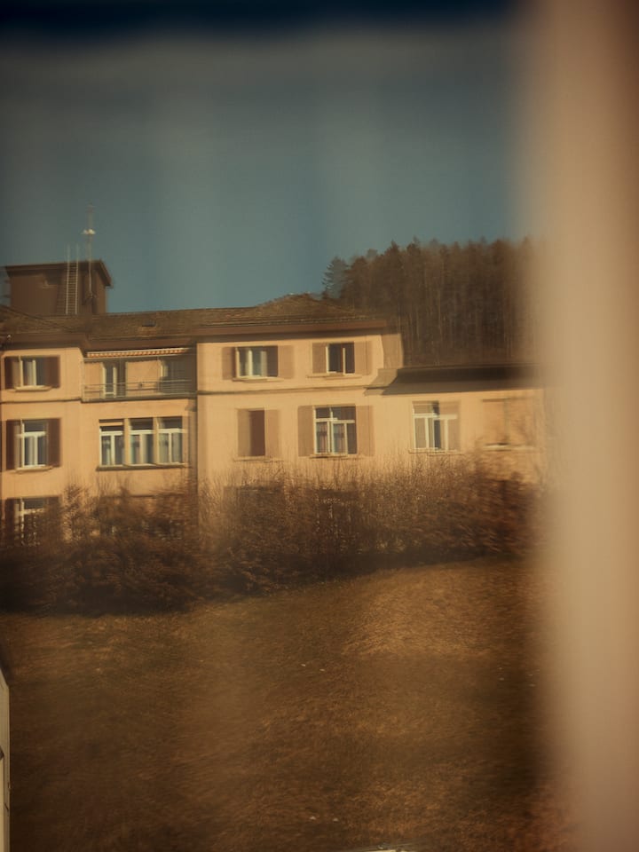 Die Fassade des Psychiatrieheims Ansbach Care in Wald spiegelt sich in einem Fenster.