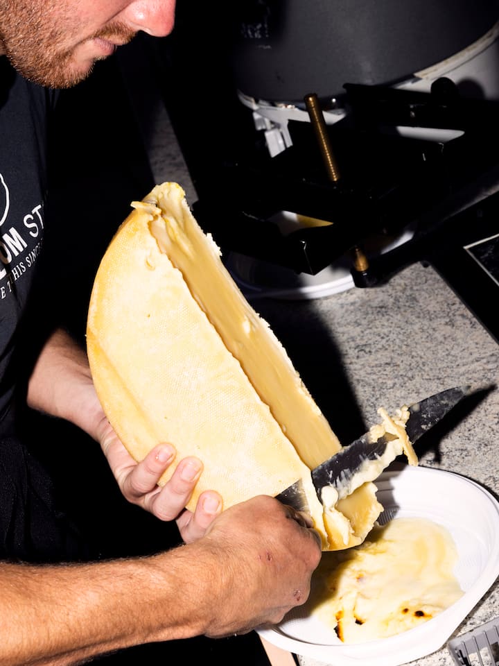 Ein Spieler vom FC Unterbaech streicht Raclette nach dem Fussballmatch FC Unterbaech gegen FC Zermatt 2 der Bergdorfmeisterschaft, in Unterbaech, Wallis, am Sonntag, 28. August 2022. (Foto: Dominic Steinmann)