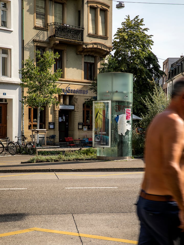 Mann oben ohne vor Telefonkabine auf dem Erasmusplatz in Basel. Drogenkrise Das Crack in unserem Quartier Im Sommer 2023 blickte die Schweiz in den Abgrund einer neuen Drogenepidemie. Ein Jahr später scheint sich die Lage beruhigt zu haben. Ein Augenschein in Basel.