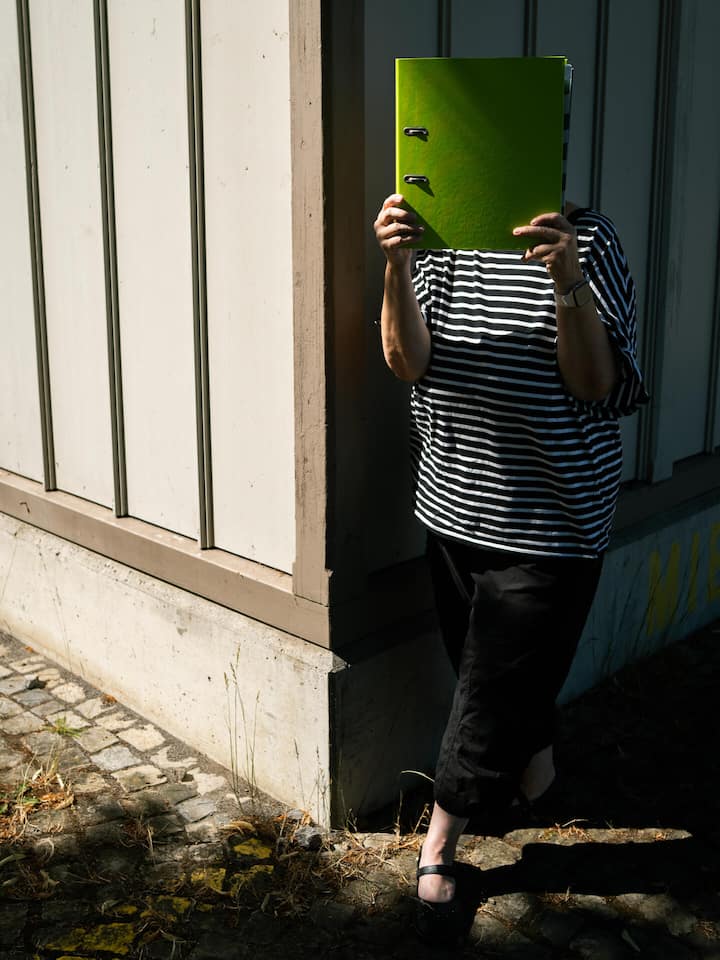 Anna Freuler (Name geändert) hält Dokumente vor dem Gesicht - Die Verfolgung der Jenischen ist ein Verbrechen gegen die Menschlichkeit. Trotzdem weigerte sich der Bund jahrelang, eine Frau als Opfer anzuerkennen