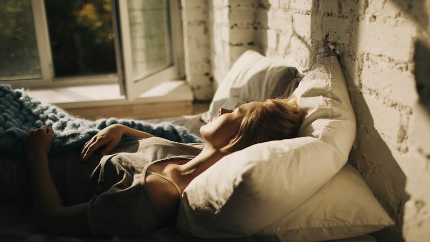 So macht der Alltag fit Frau schläft bei offenem Fenster im Bett