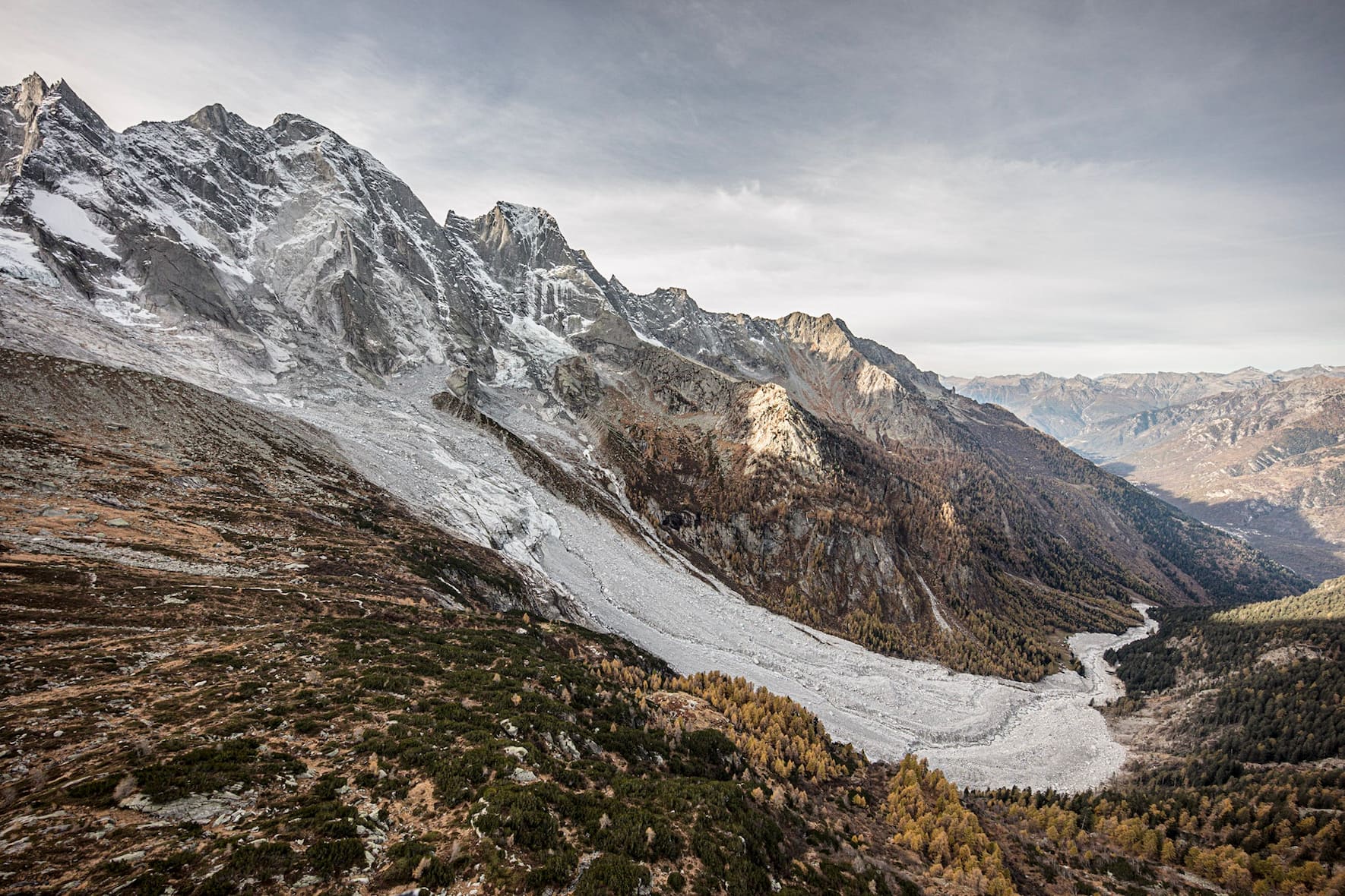 Die grauen Geröllmassen eines grossen Bergsturzes liegen am Hang eines Berges und gehen bis ins Tal.
