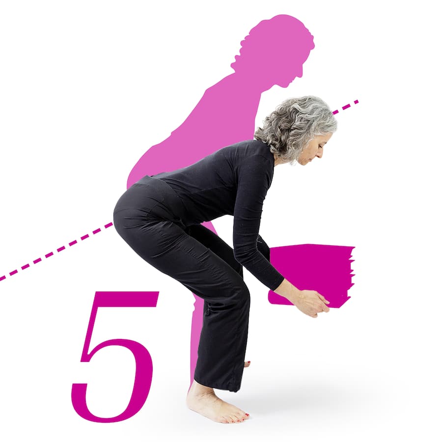 Eine Frau hebt einen Stapel Bücher vom Boden auf.