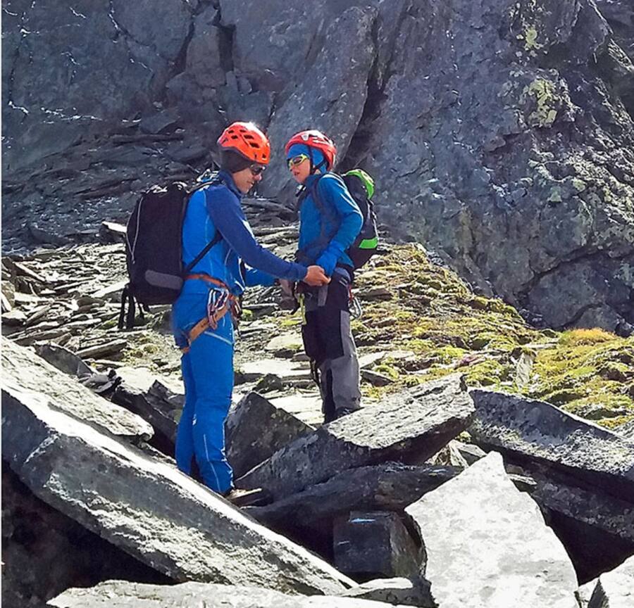 Bergführer hilft Kind mit Kletterausrüstung