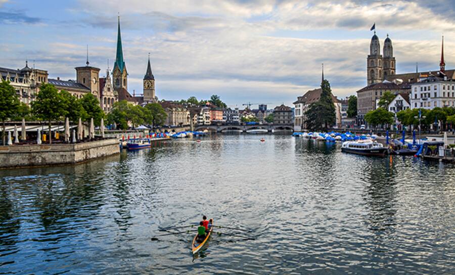 Das Ruderboot gleitet über die Limmat, im Hintergrund die Skyline von Zürich mit dem Fraumünster,