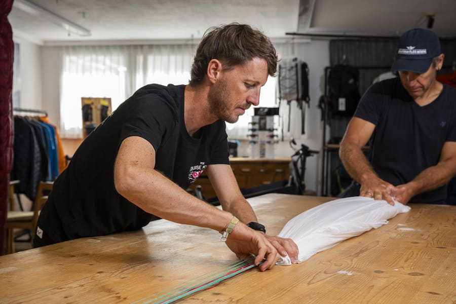 BÜHLER, AR 09.082026 - Fabio Zgraggen, der auch als Fluglehrer arbeitet, im Geschäft seiner Flugschule "Freewings" in Bühler AR. Hier mit seinem Geschäftspartner Sam Schlaberg bei der jährlichen Kontrolle eines Notschirms.Photo by Pascal Mo…