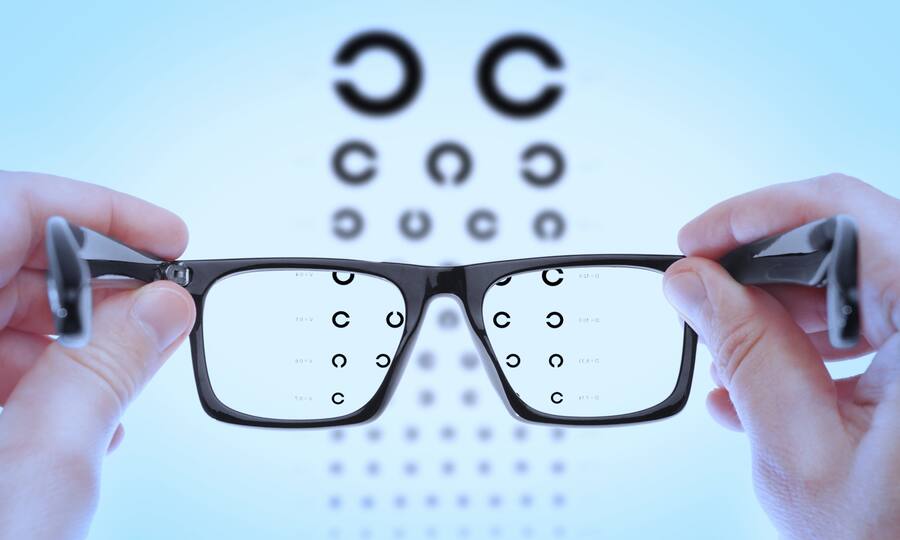 Eine Brille, die vor einen Sehtest gehalten wird, kann sprichwörtlich als Lesehilfe für den Ausweis der Pensionskasse dienen.