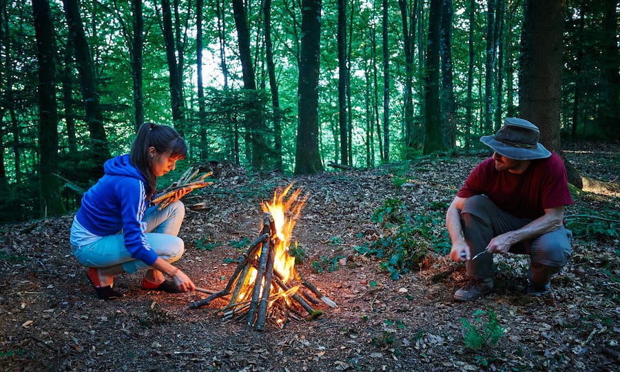 Ein kleines Pyramidenfeuer wird im Wald entzündet.