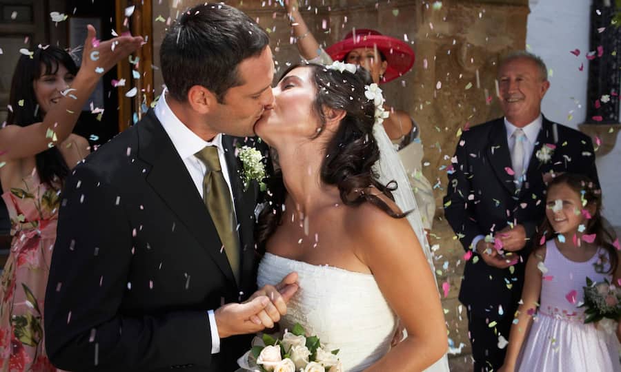 Ein frisch vermähltes Paar küsst sich an seiner Hochzeitsfeier.