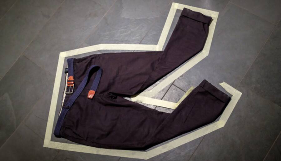 Eine Hose liegt auf dem Boden und ist mit Klebeband umrahmt wie an einem Tatort