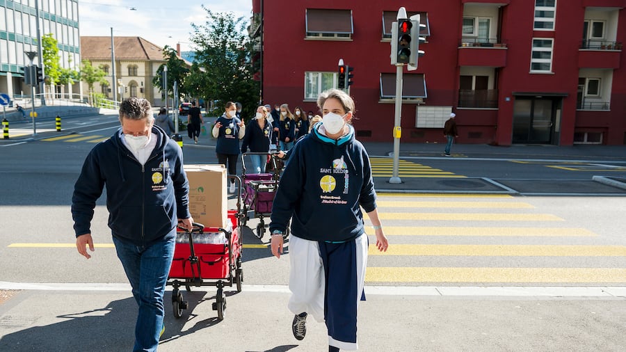Freiwillige ziehen Wägeli mit Lebensmitteln und Produkten des täglichen Bedarfs durch den Zürcher Kreis 4
