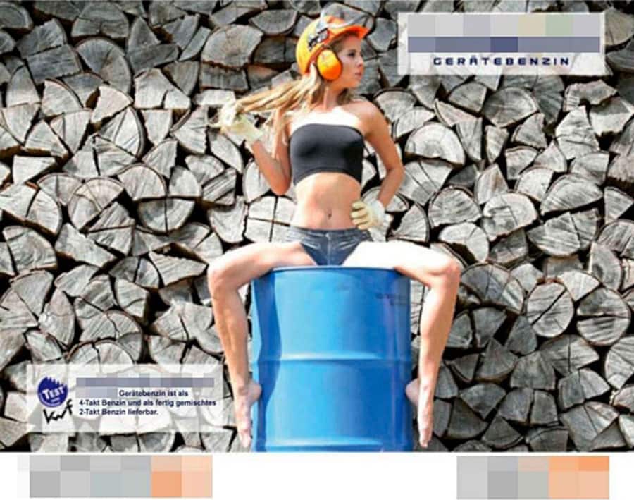 Eine leicht bekleidete Frau, die mit weit gespreizten Beinen auf einem Fass sitzt und mit ihrem Haar spielt. Dazu steht das Wort: «Gerätebenzin».