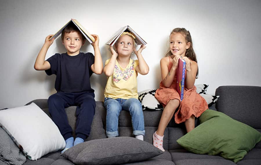Die Kinder Louis, Elena und Franca halten drei Kinderbücher hoch.