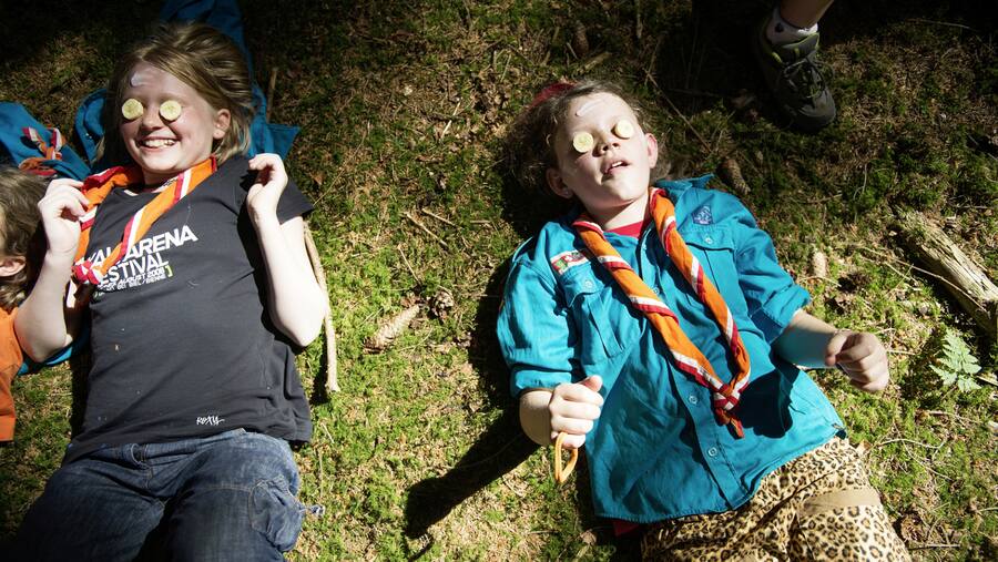 Zwei Pfadfinderinnen liegen auf einer Wiese mit einer natürlichen Gesichtsmaske