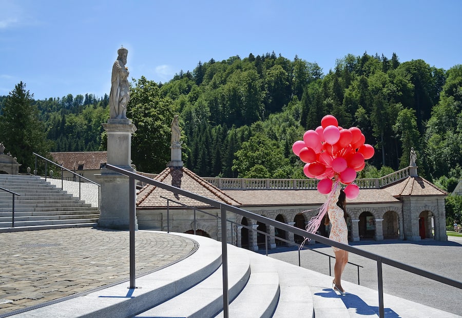 Frau mit Ballonen posiert auf der Klostertreppe in Einsiedeln