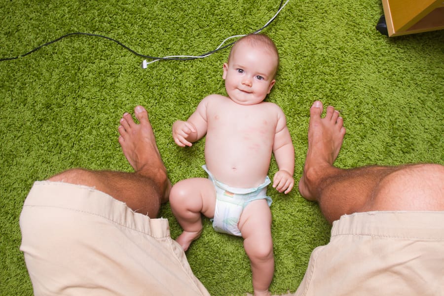 Baby liegt Vater zwischen Füssen. Maternal Gatekeeping, Mental Load und Erschöpfung - Ein Gespräch mit Psychologin Valentina Rauch-Anderegg über die Tücken des modernen, gleichberechtigten Elternlebens.