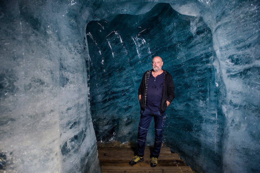 Der ehemalige Grottenchef William Jerjen steht in der Eishöhle, am Boden Holzplatten, die Wände aus blauem Eis