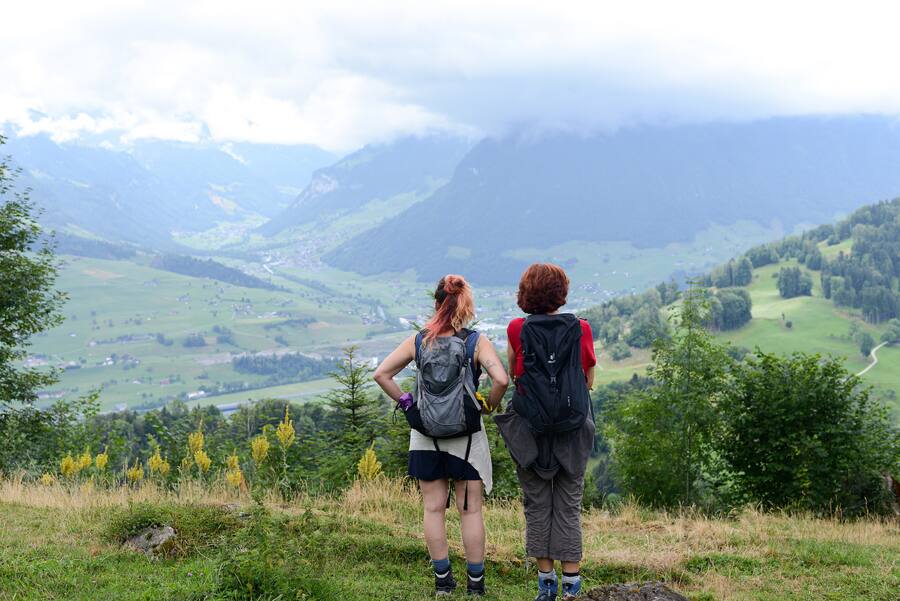 Jana Avanzini und Jacqueline Egger stehen an einem Hang – vor ihnen eine Aussicht über Felder, Hügel, Dörfer