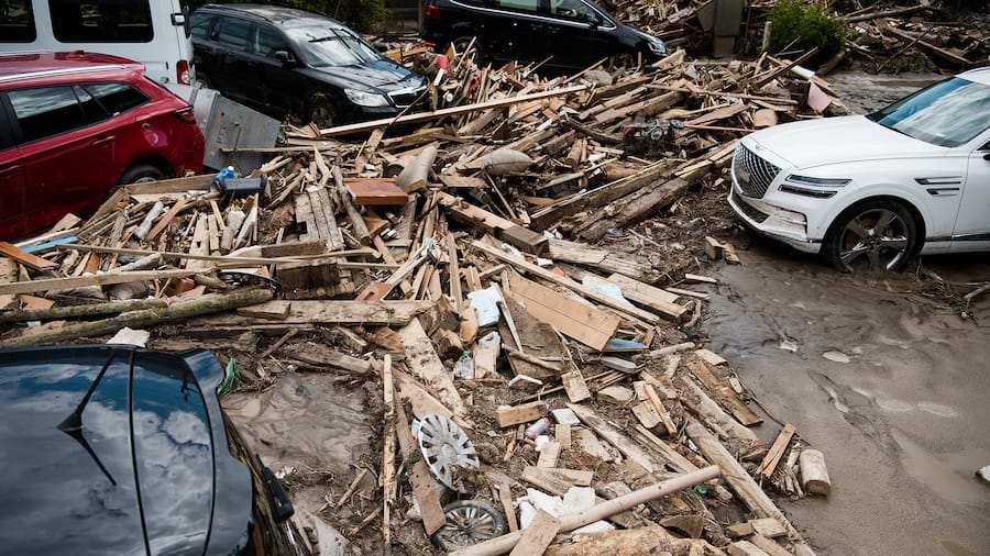 Autos und kaputtes Holz stecken im Schlamm fest.