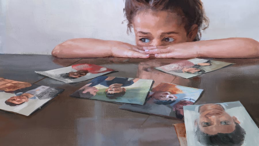 In der Illustration sitzt ein Mädchen an einem Tisch, und schaut mit ängstlichen Augen über ihre hingelegten Arme auf Fotos auf dem Tisch.