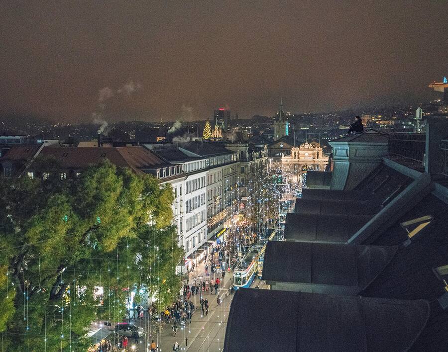 Ein Jugendlicher sitzt auf dem Dach und überblickt die Zürcher Bahnhofstrasse