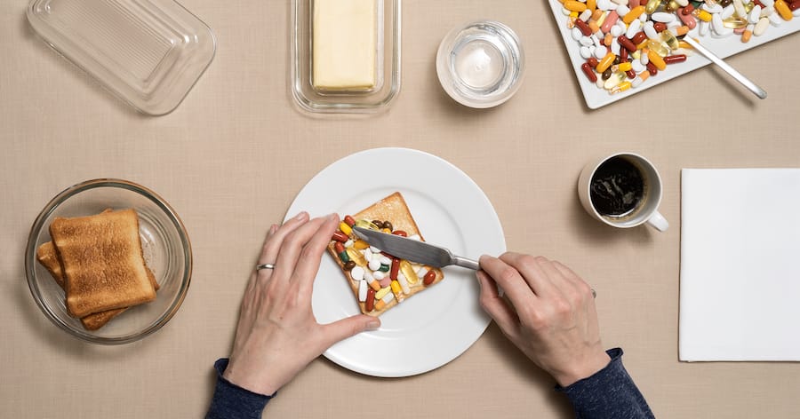Bild einer Frau, die ein Toasbrot mit Tabletten bestreicht.