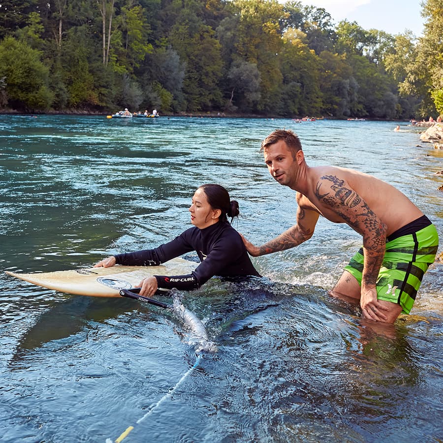 Surfinstruktor hilft Schülerin.
