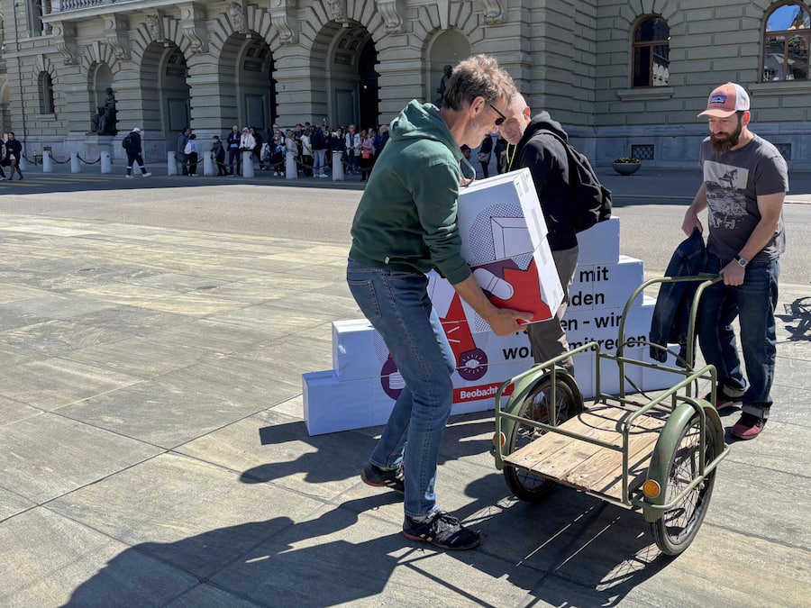 Die Schachteln mit einem Veloanhänger - Der Beobachter hat dem Parlament die Prämien-Petition mit fast 50’000 Unterschriften übergeben. Die Kernforderung: Wer die Milliarden zahlt, muss am Verhandlungstisch endlich ein Mitspracherecht erhalten